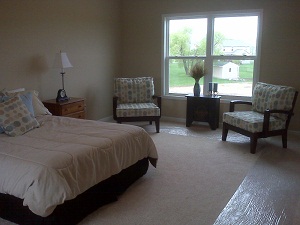 Spacious bedroom with a bed and two chairs in Rochester, NY