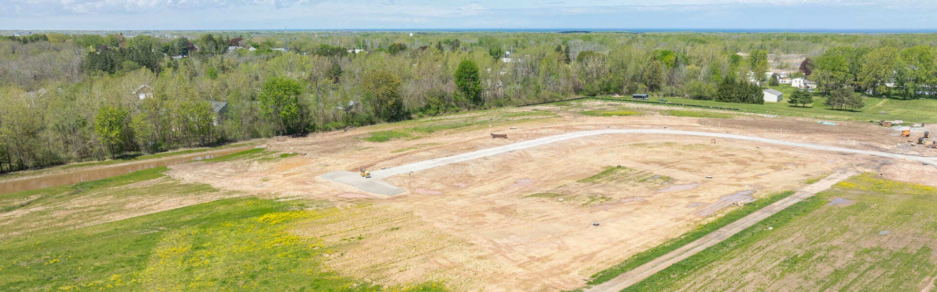 Aerial view of new residential development site in Greater Rochester, NY with graded lots and curved road