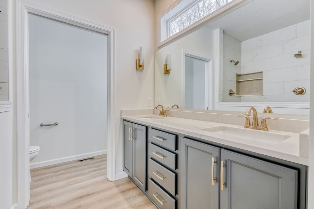Bathroom in Rochester area custom home by Gerber Homes with double vanity and brass finishes