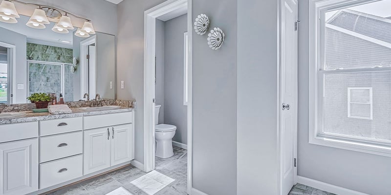 Master bathroom with white shaker cabinets on double vanity and private toilet area