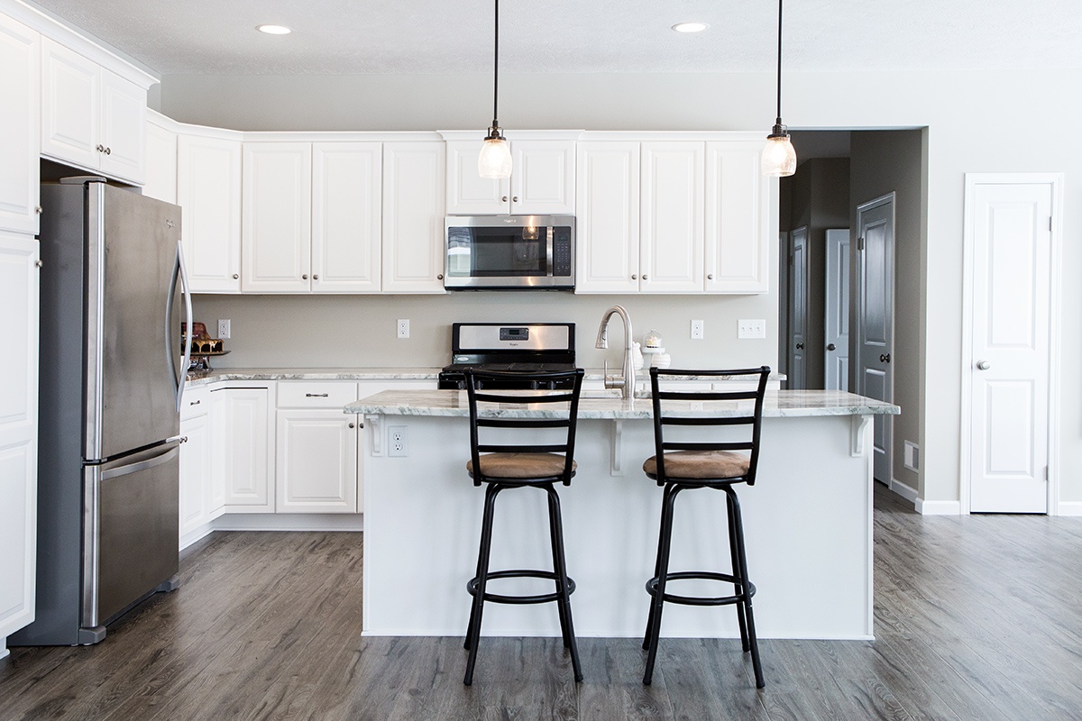 Bright kitchen in Rochester, NY, with white cabinets, island seating, and stainless appliances.