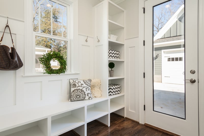 Bright white mudroom with built-in storage, bench seating, and window decor located in Rochester