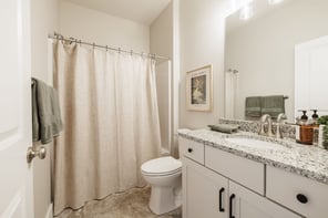 Greater Rochester bathroom with granite vanity, brushed nickel faucet, white shaker cabinets, and linen shower curtain