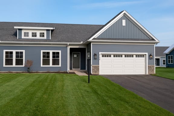 Greater Rochester blue ranch style home exterior with dormer, stone veneer garage accents, and manicured lawn