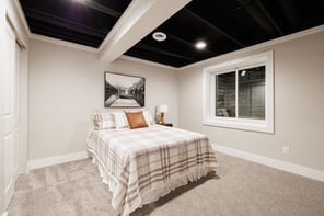 Greater Rochester finished basement bedroom with black painted ceiling, plaid bedding, and egress window
