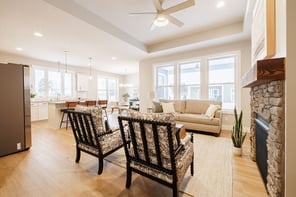 Greater Rochester open concept living room with tray ceiling, stone fireplace, and white kitchen with island seating