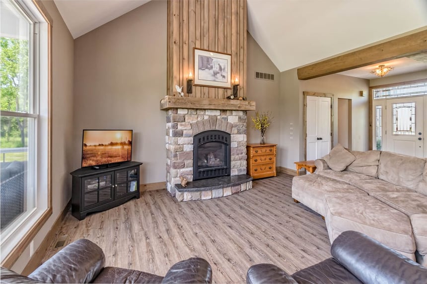 Custom-built family room space with vaulted ceiling and stone fireplace with sculpted wood mantel