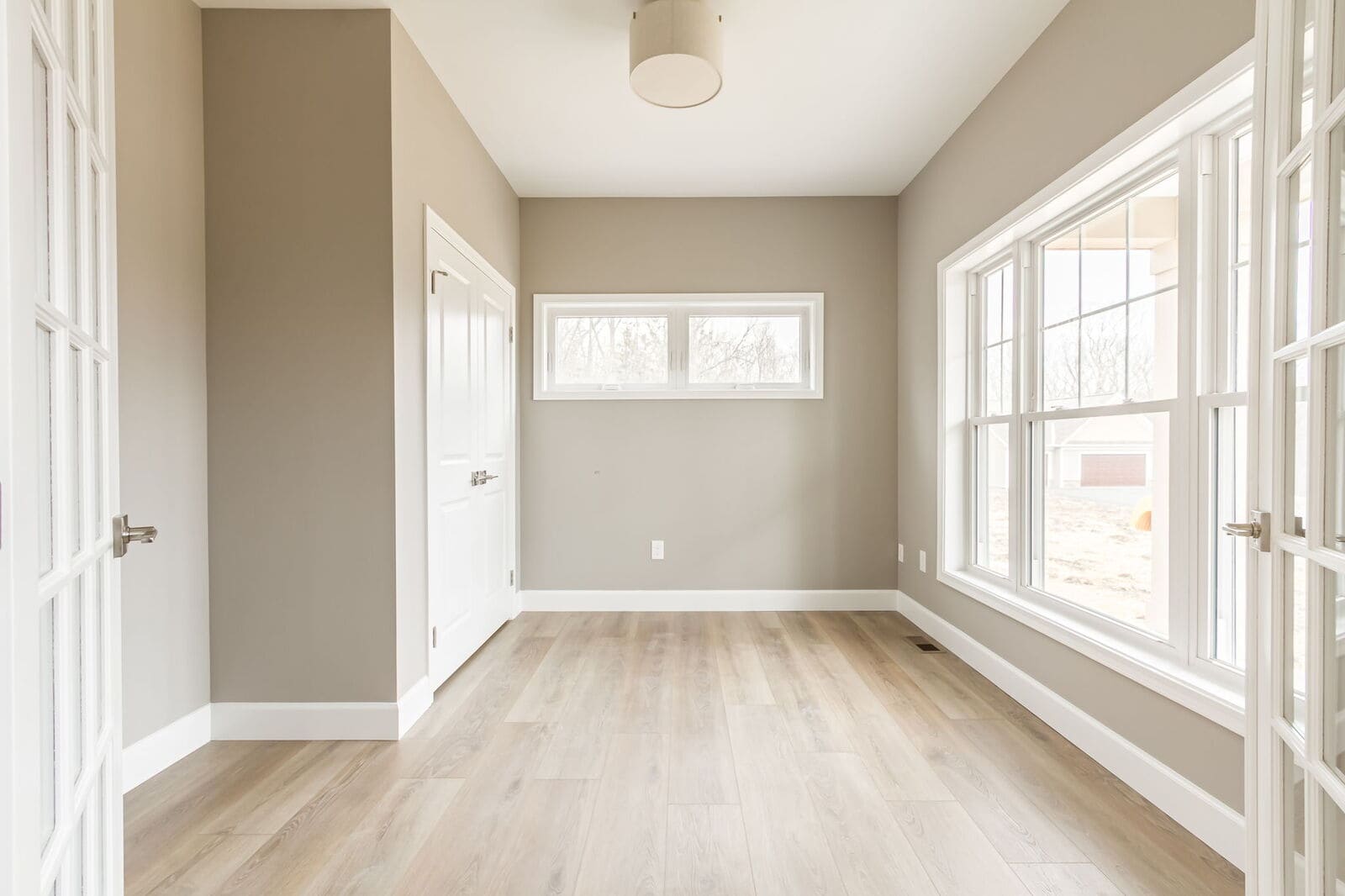 Bright home office with large windows and light wood flooring in a new Canandaigua home.