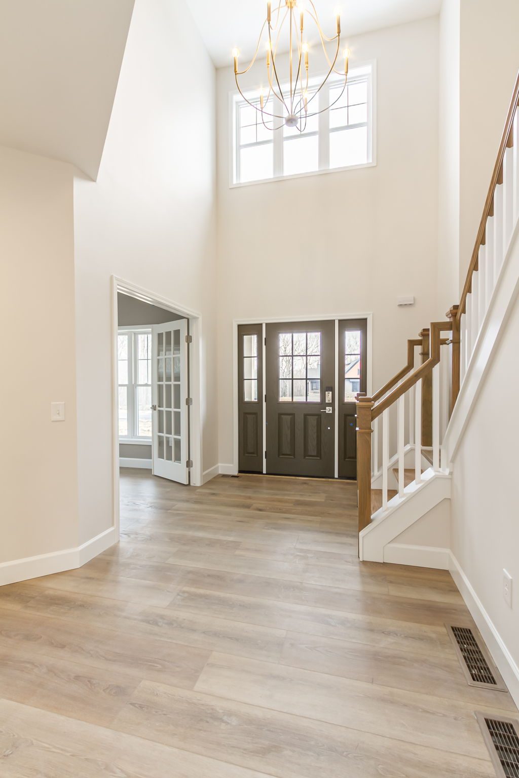 Foyer with tall window, chandelier, and view into french doors