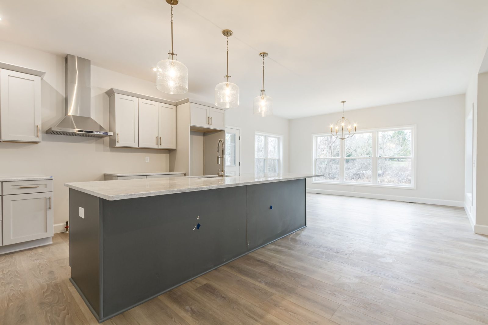 Kitchen island with gold pendant lights and view into dining area