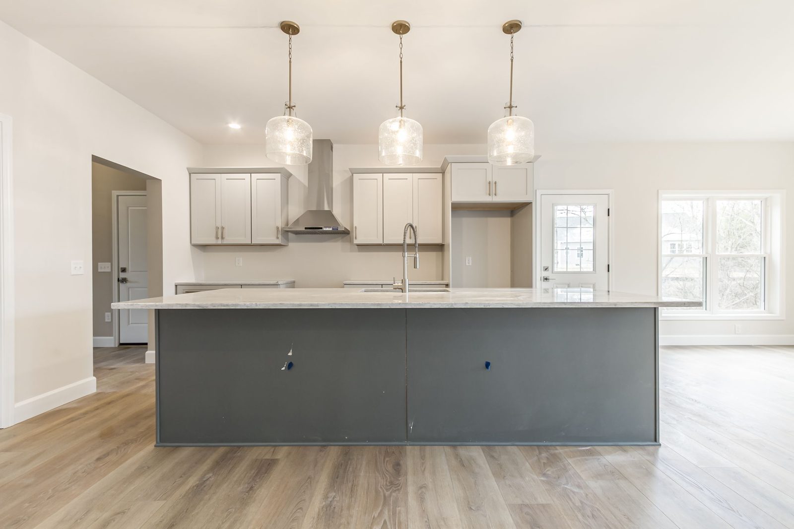 Kitchen island with pendant lighting and back door to backyard