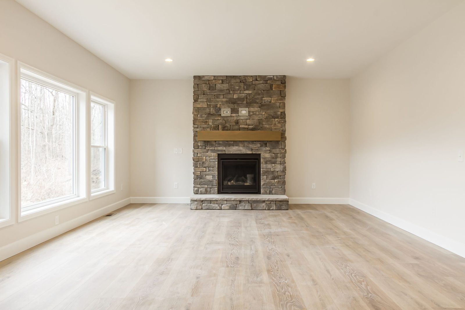 Living room stone fireplace with wood mantel, close view
