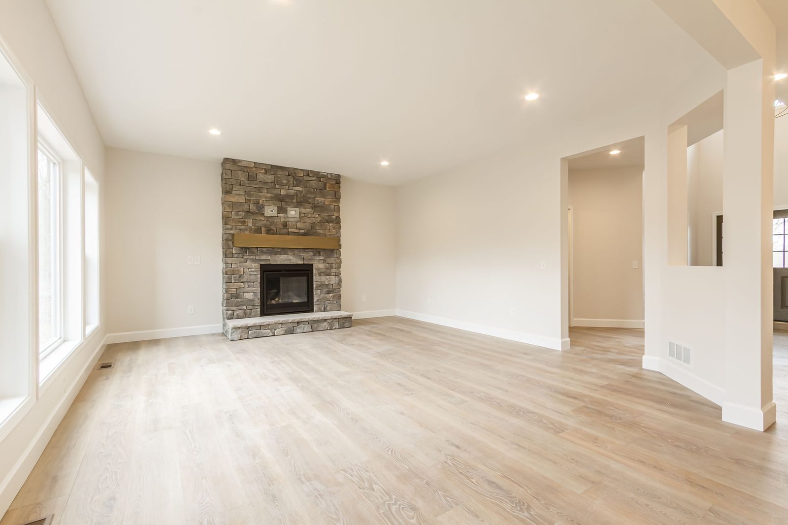 Living room with stone fireplace and hallway toward kitchen