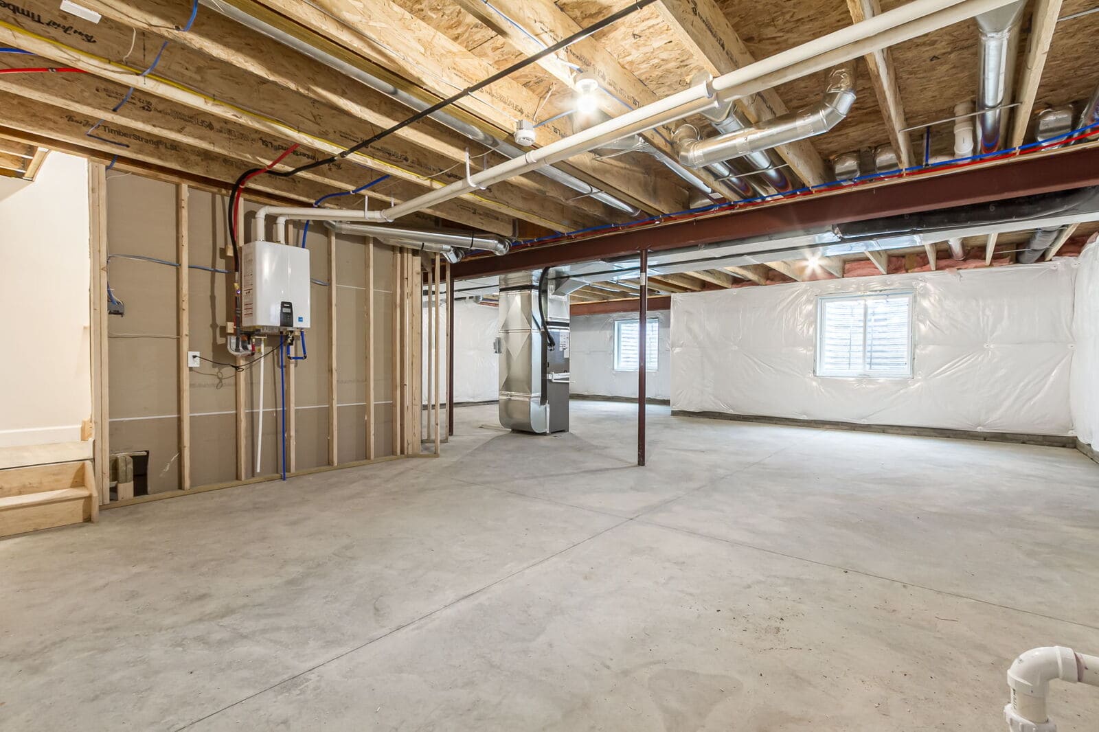 Spacious unfinished basement with concrete floors, exposed framing, ductwork, plumbing, and mechanical systems.