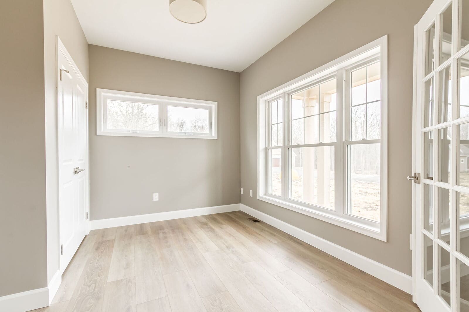 Sunlit home office with French doors and large windows in a new Canandaigua home.
