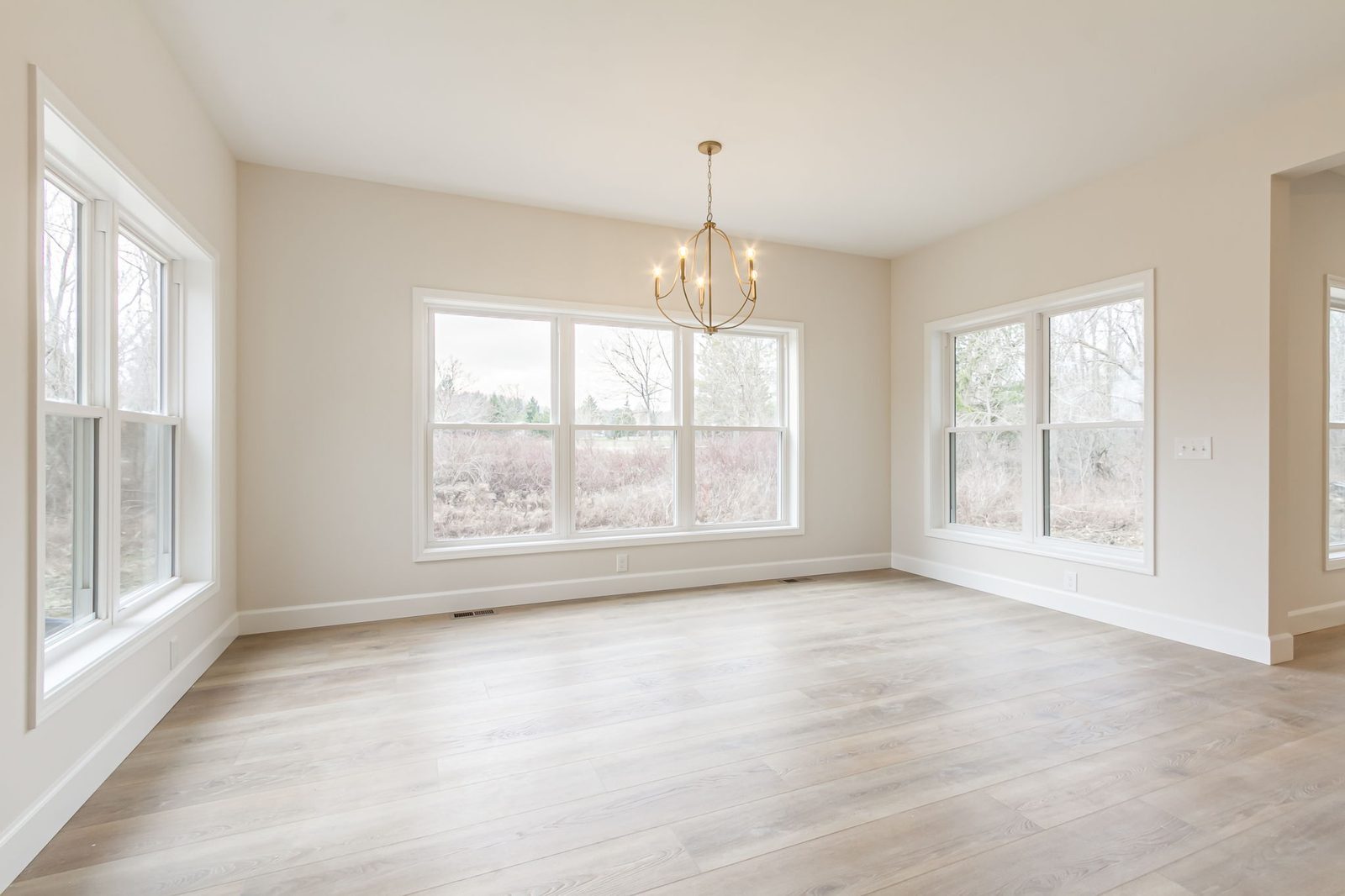 Sunny breakfast nook with large windows and gold chandelier