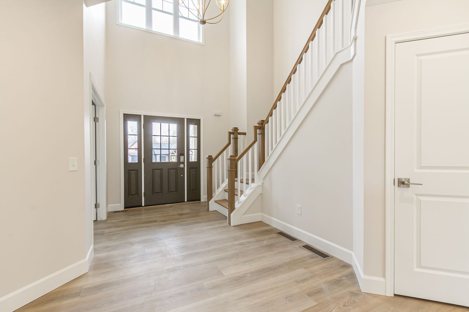 Two-story foyer with wood and white staircase leading up from front door