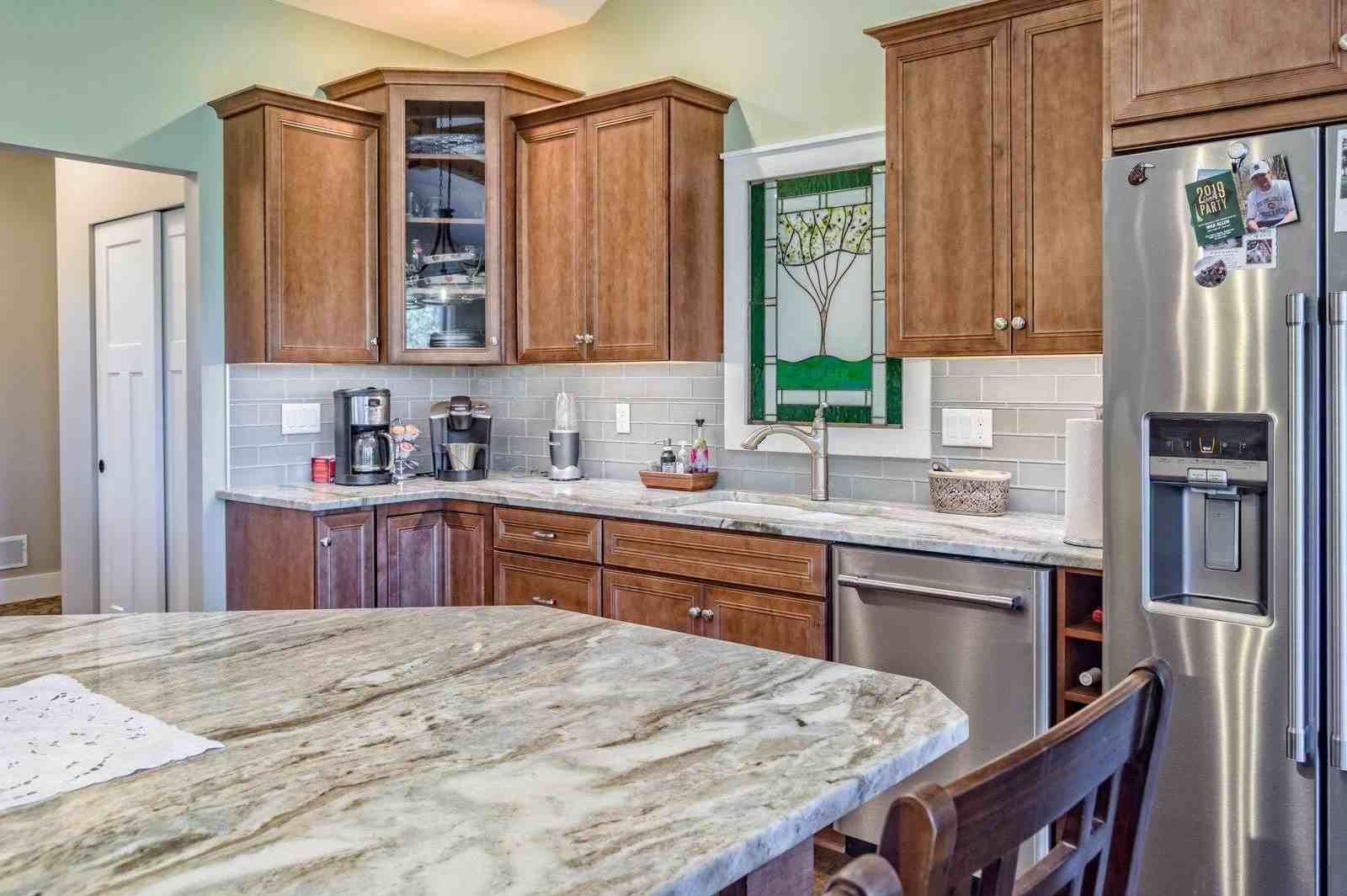 Custom Kitchen with Granite countertops, large kitchen island, stain glass window, tiled backsplash, cabinets with glasses doors by Gerber Homes 228 Ridge Road