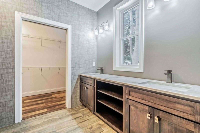 Custom Master bathroom in Rochester NY, with attached walk-in closet, custom wooden vanity, and hard wood floors