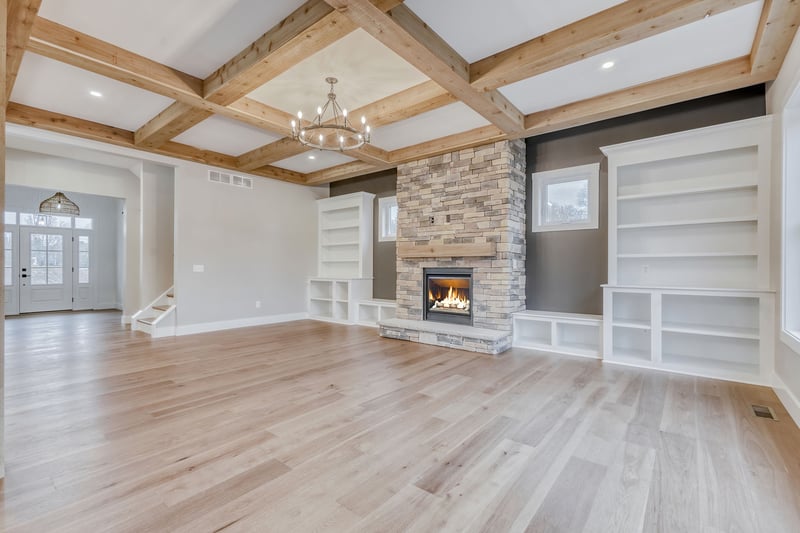 Main floor of luxury custom home with built-in shelving and stacked stone fireplace in greater Rochester