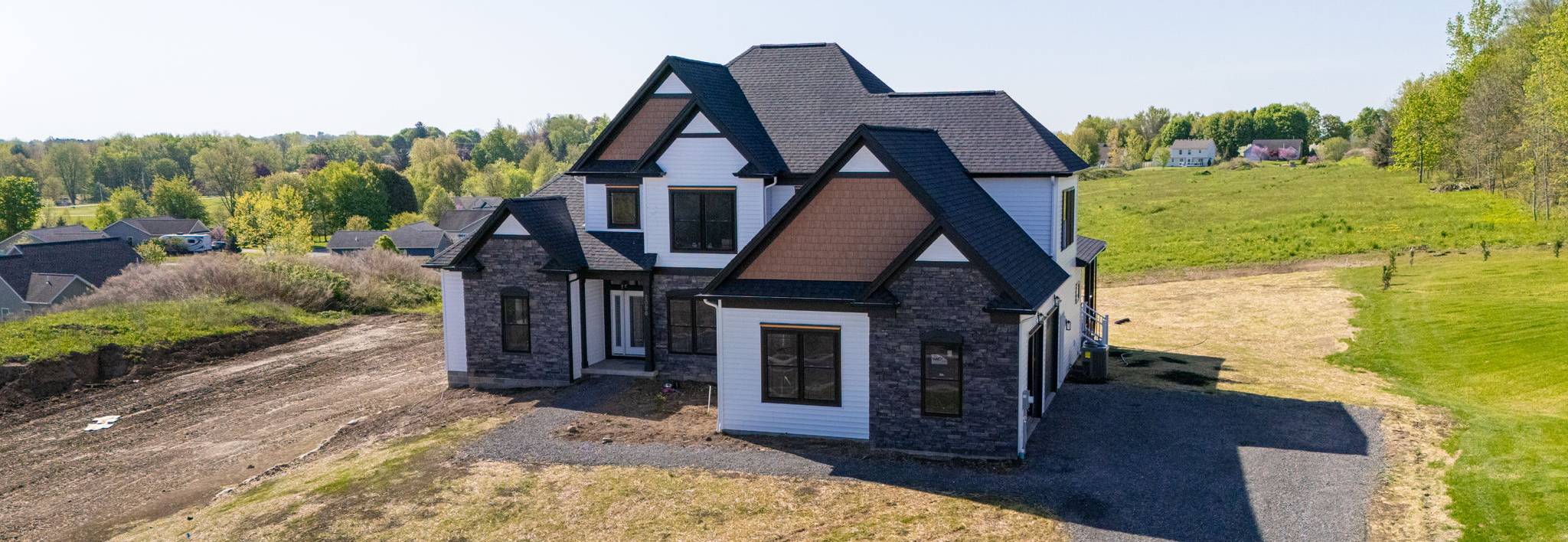 Modern custom home with stone accents, black trim, and steep gabled roof in Rochester, NY Modern custom home with stone accents, black trim, and steep gabled roof in Rochester, NY