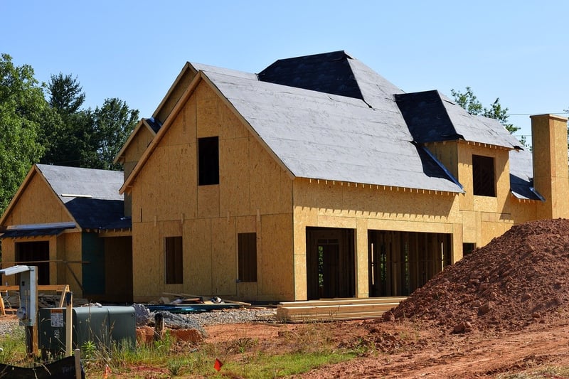New Rochester area home under construction with wood framing and roof sheathing at a building site