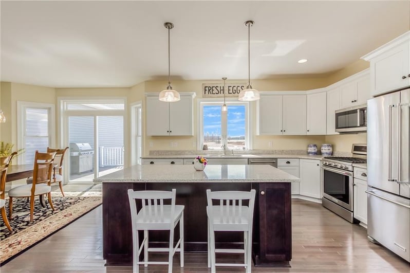 Bright kitchen with island seating, white cabinets, stainless appliances, and dining area by Gerber Homes