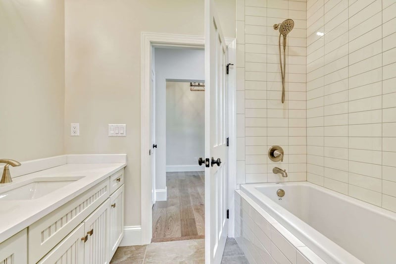 Custom Bathroom with tiled bath, white wooden vanity, and granite countertop