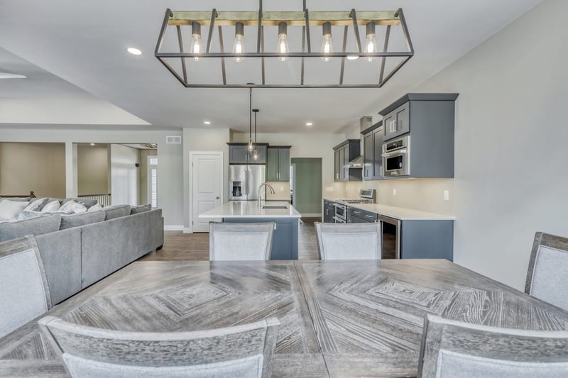 Open-concept interior of custom home main level with modern light fixture above dining room table