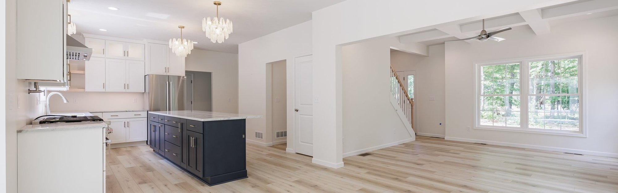 Open-concept kitchen and living area with large island and light wood floors in a Rochester, NY home