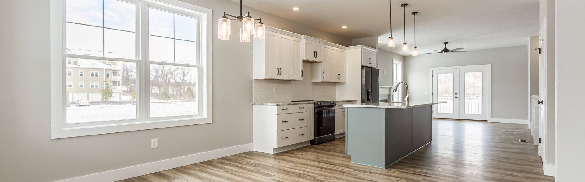 Open-concept kitchen and living area with white cabinets, large island, and wood flooring in a Greater Rochester home Open-concept kitchen and living area with white cabinets, large island, and wood flooring in a Greater Rochester home