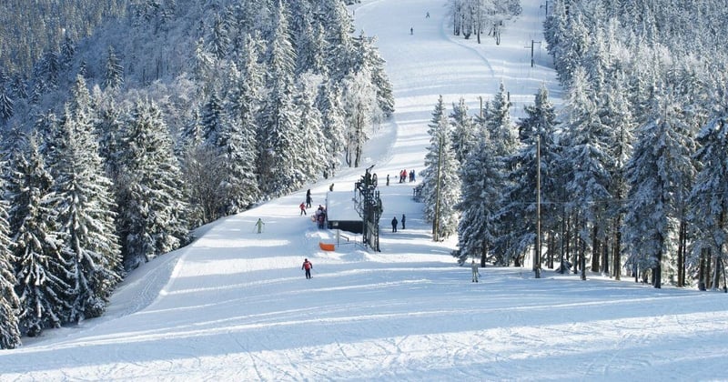 Ski resort view of slope with multiple skiiers going down