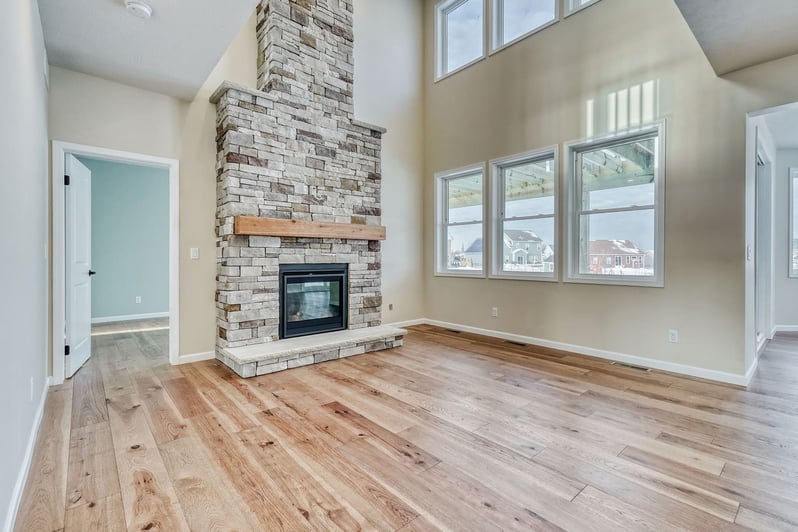 Spacious Upstate New York living room with stone fireplace and large windows by Gerber Homes