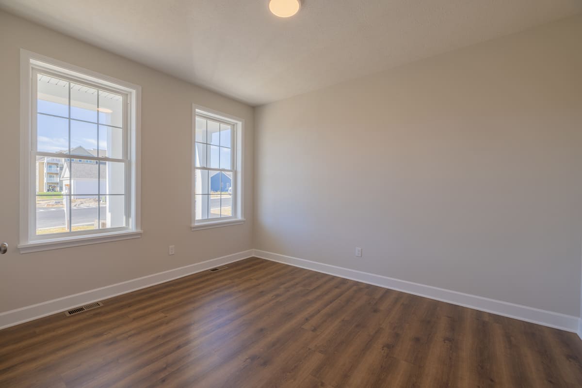 Room with two windows in The Cottages of Canandaigua home with hard wood flooring