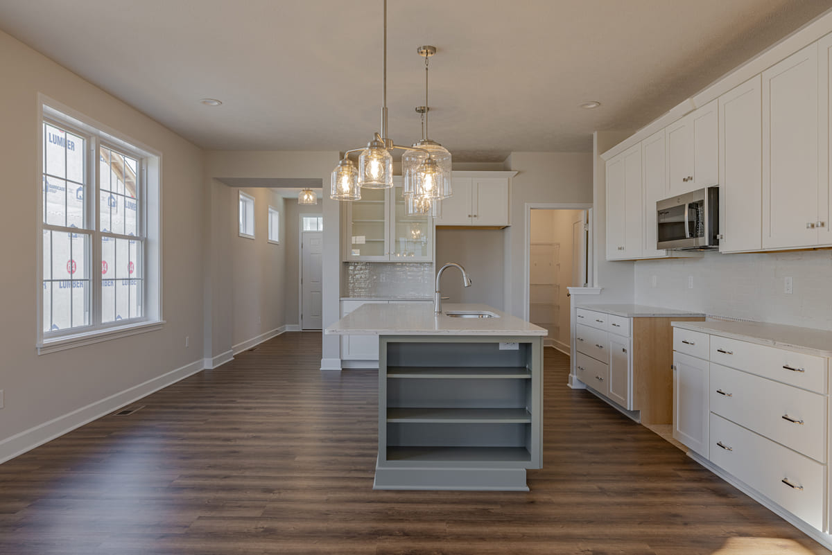Single wall kitchen with island with hanging glass light fixture in The Cottages of Canandaigua home