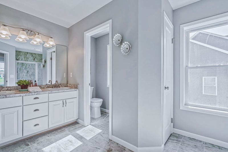 Master bathroom with white shaker cabinets on double vanity and private toilet area
