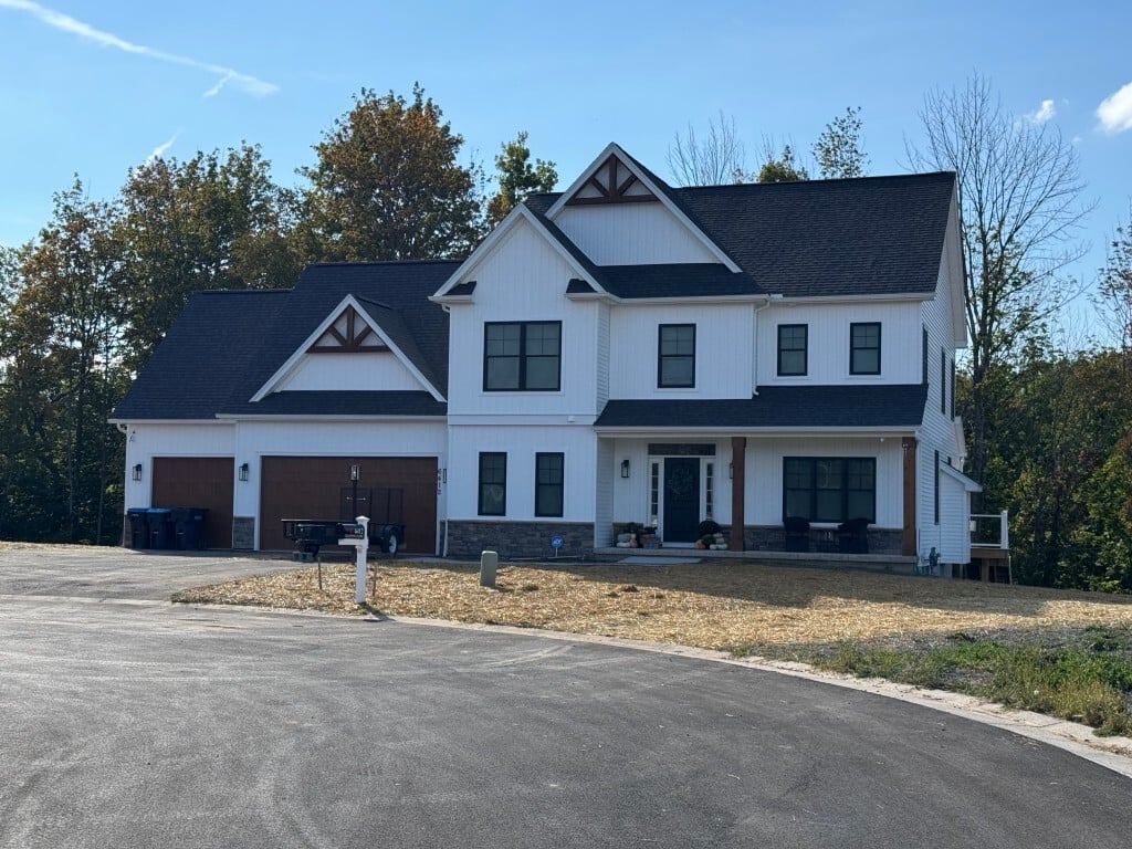 Two-story white house with dark trim in the Rochester, NY area, viewed from a cul-de-sac