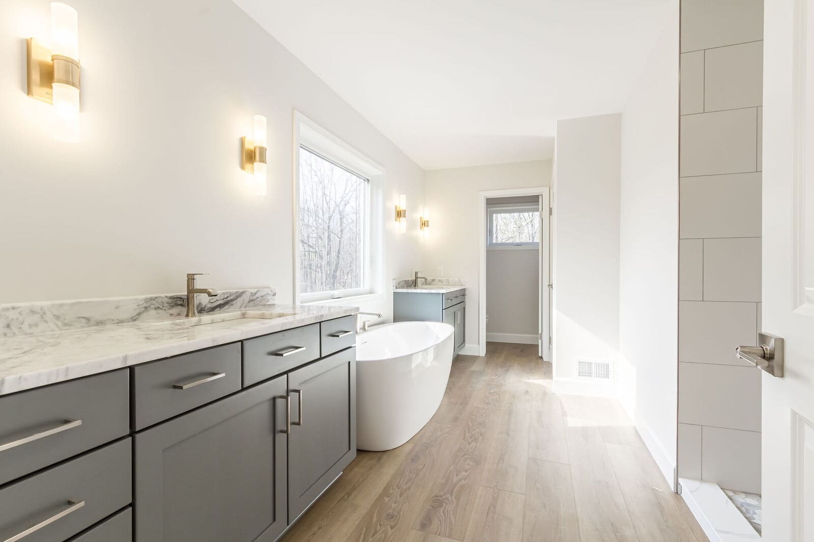 Primary bathroom with dual dark vanities, freestanding tub, and tiled shower