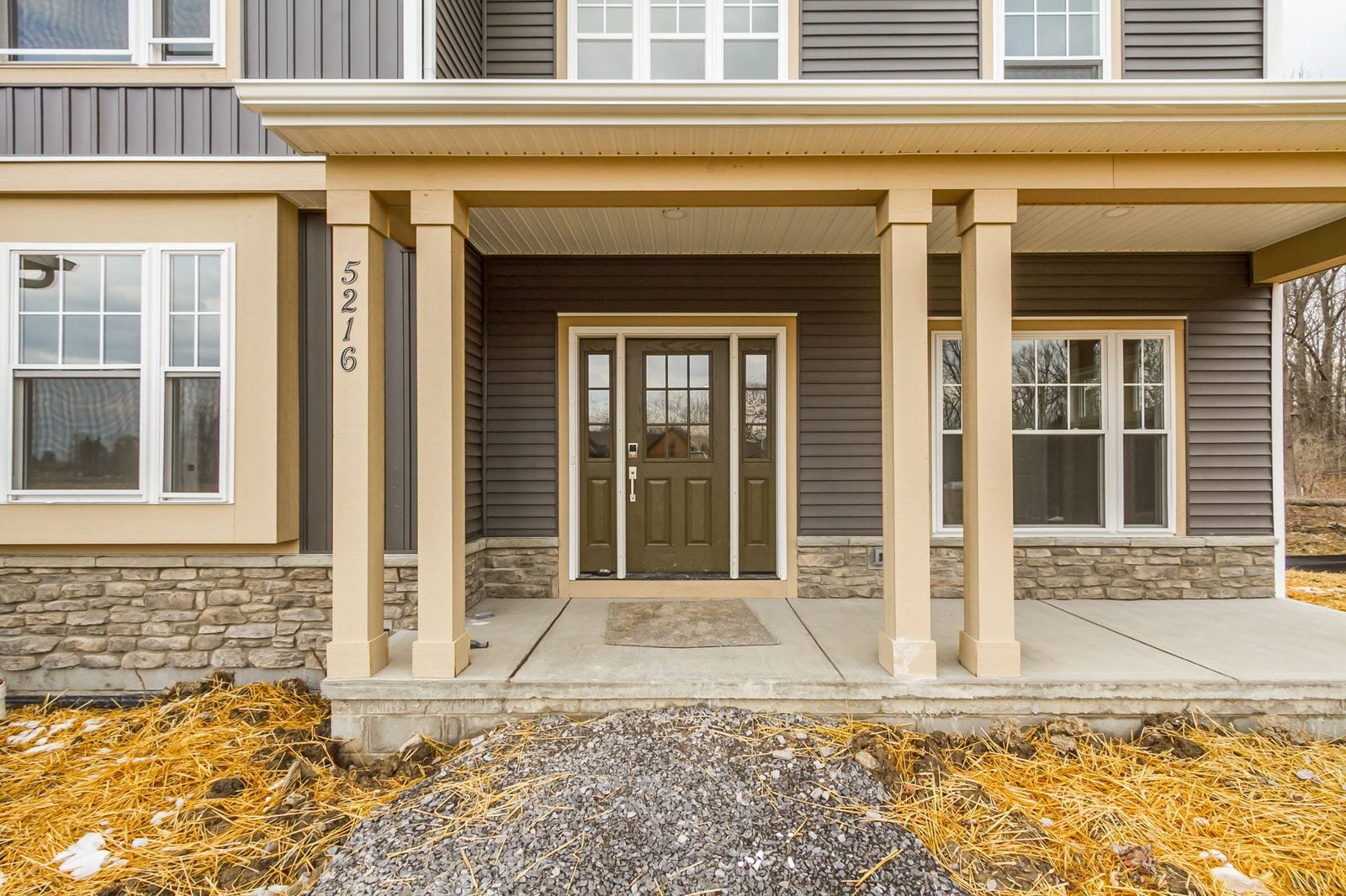 Covered front porch with stone accents and olive green front door