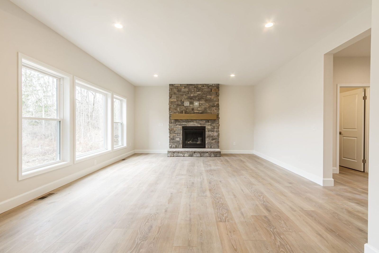 Living room with stone fireplace and wall of windows