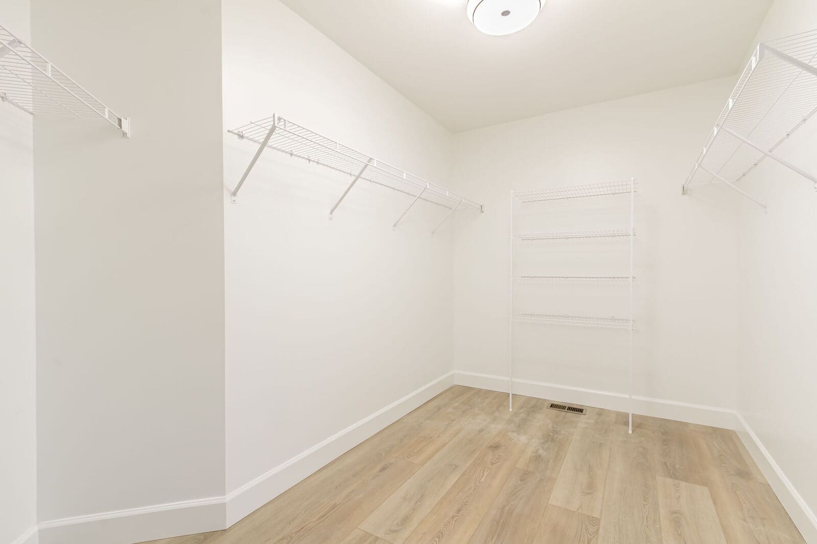 Walk-in closet with shelving and light wood flooring