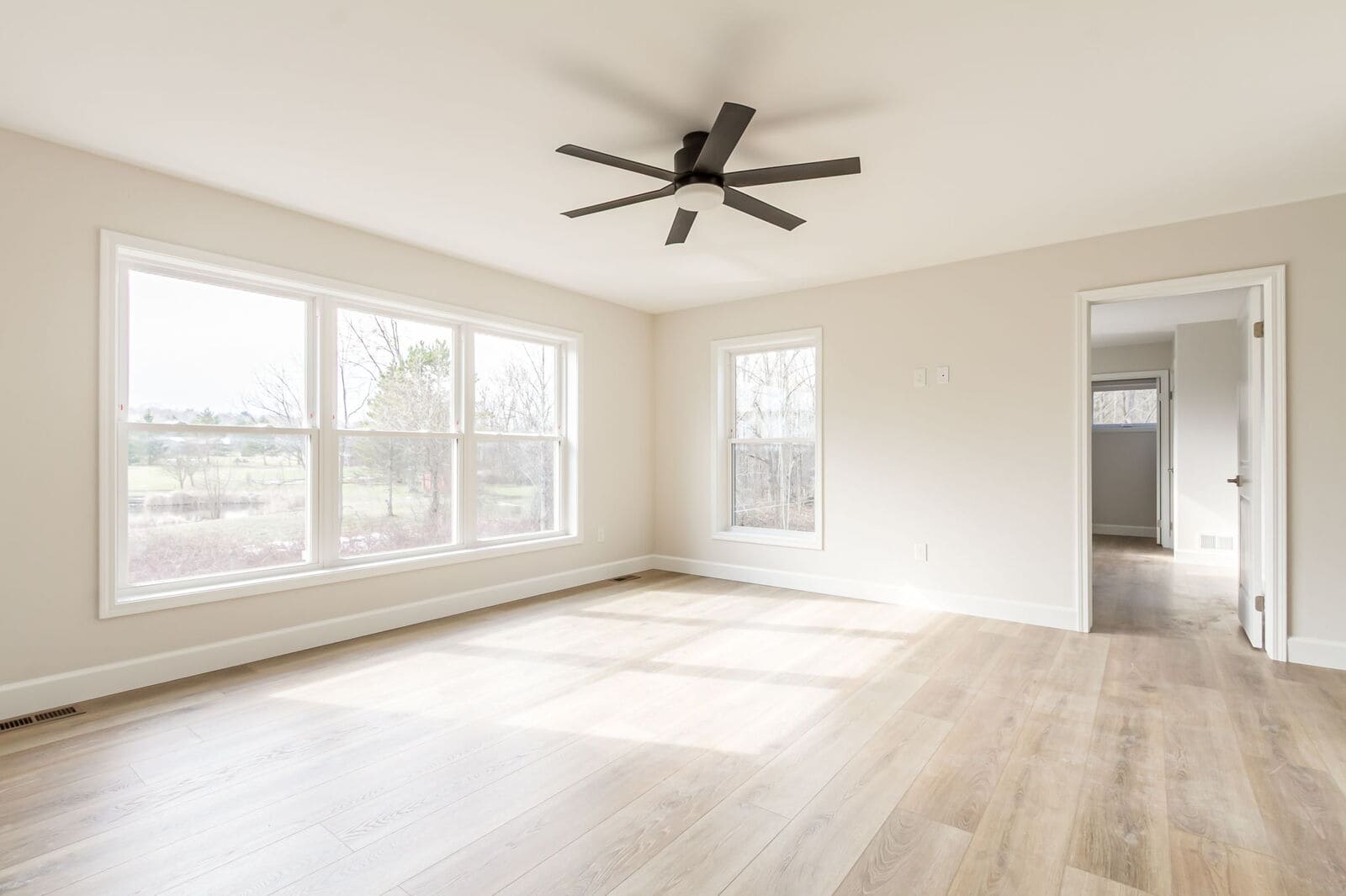 Primary bedroom with large windows and light wood flooring