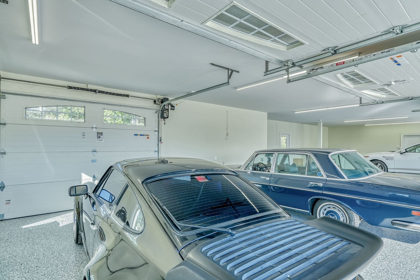 Finished multi-car garage with epoxy floor, bright lighting, and space for a classic car collection