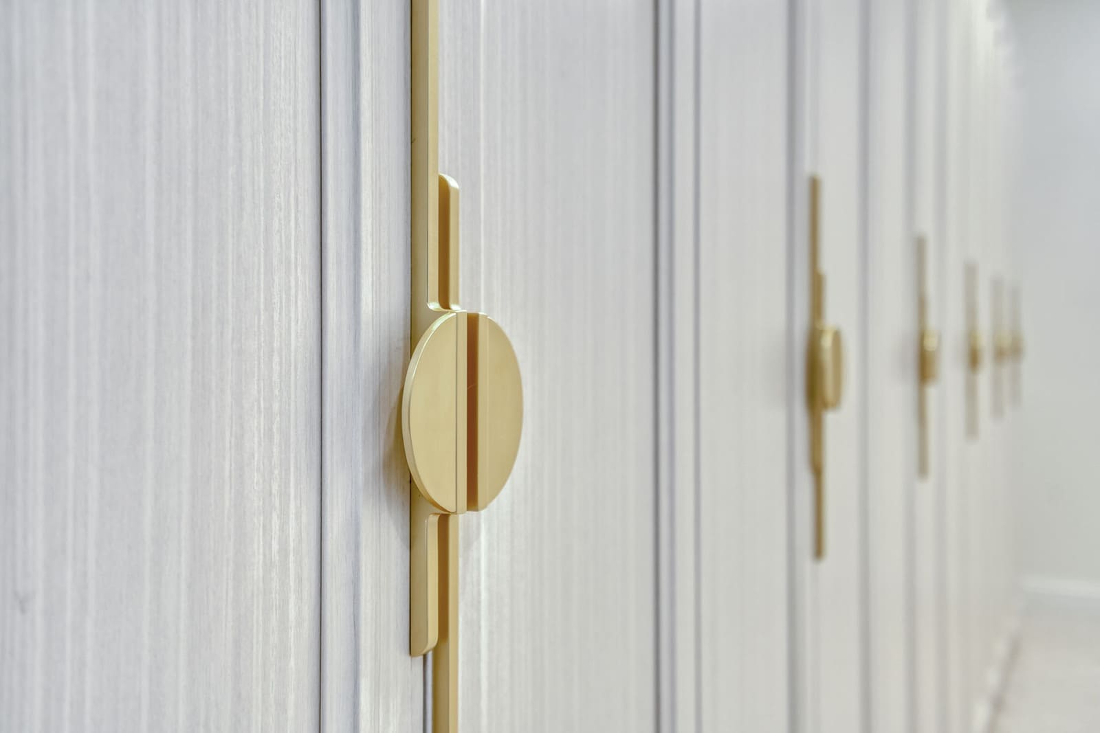 Primary closet detail with textured cabinet fronts and modern brushed-gold hardware
